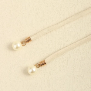 Detail of beige suede cord belt with gold metal connector and white faux pearl decoration