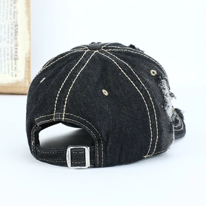 Detail of washed denim baseball cap featuring distressed holes and metal buckle strap