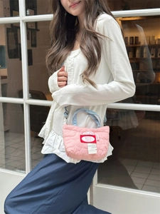 Dettaglio mini borsa trapuntata rosa con cuciture a cuore e manici in denim blu