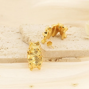 Boucles d'oreilles créoles dorées plissées en forme de C sur un socle en pierre