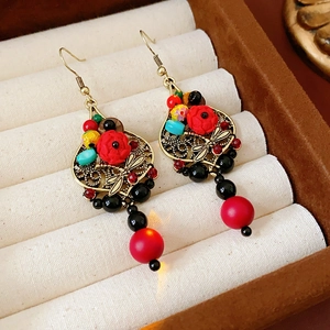 Detail of vintage bohemian tassel earrings with red floral accents and colorful beads
