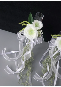Close-up of elegant wedding champagne glass decor with white camellias and silk tassels