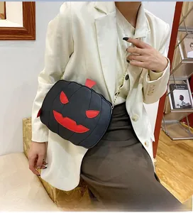Detail view of a pumpkin-shaped Halloween handbag with red facial features and gold chain