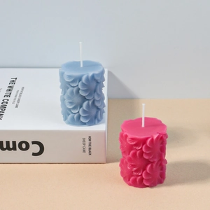 Detaillierte Reliefblumenmuster auf blauen und rosa Duftkerzen in Zylinderform