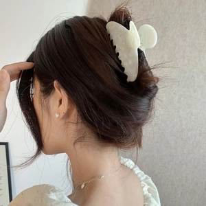 Detail view of a white marble acetate claw clip styled on a woman's hair in a low bun