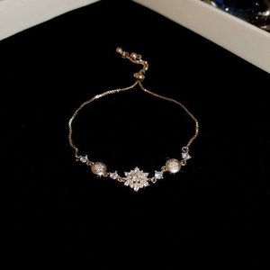 Detailed macro view of golden zircon flower bracelet with adjustable slider clasp on black velvet