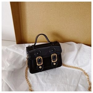 Detail view of mini crossbody bag in black patent leather with gold chain strap decoration