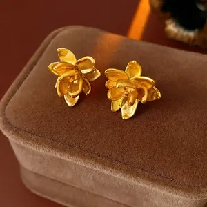 Retro gouden lotusbloem oorknopjes met matte metaalafwerking op donker fluweel