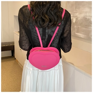 Rear view of a model wearing a pink heart-shaped PU leather backpack for fashion styling