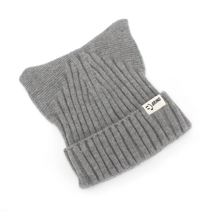 Détail d'un bonnet en maille gris avec oreilles de chat et étiquette logo smiley
