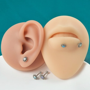 Detail view of G23 titanium opal flower lip rings and cartilage studs on silicone models
