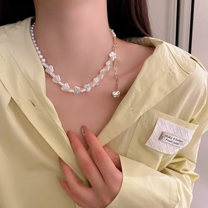 Detailed close-up of irregular pearl heart pendant necklace on female model neck
