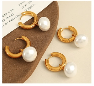 Macro shot of gold hoop earrings with lustrous white pearl pendants on a warm background