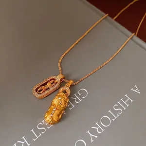 Gold PiXiu necklace with zircon pendants over an old book showing cultural elegance