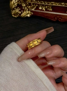 Detailed view of a vintage gold ring featuring star patterns and zircons on a hand.