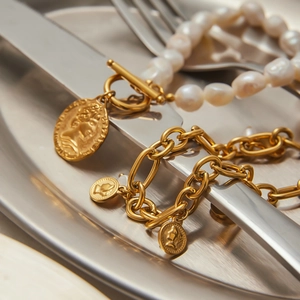 Detailed macro view of gold toggle clasp bracelet with baroque pearls and coin charms