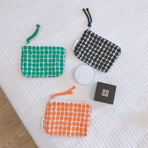 Close-up of three colorful floral canvas pouches with dot patterns and rope zipper pulls