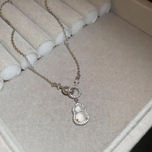 Detailed close-up of a silver zircon gourd pendant necklace on a gray velvet jewelry box