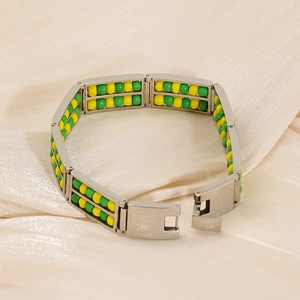 Detail of silver steel bracelet with yellow and green stone beads on silk fabric