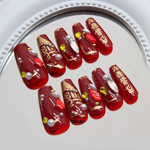 Burgundy and gold festive press-on nails with 3D rhinestones and pearls on a white mirror