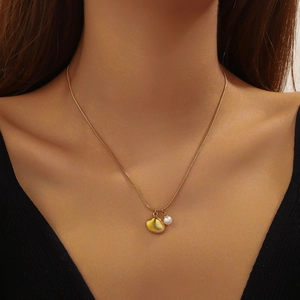 Gold-plated stainless steel shell and pearl pendant necklace worn by a fashion model