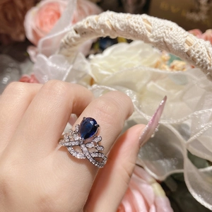 Detailed close-up of a silver crown ring with a pear-cut blue sapphire and pavé diamonds