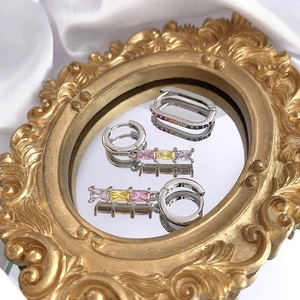 Detailed shot of gold earrings set with colorful zircon stones on a vintage mirror