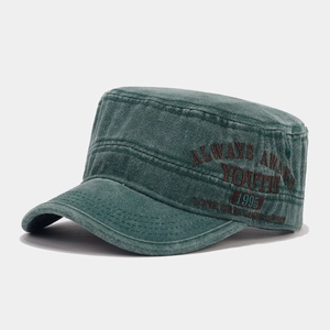 Detail of washed cotton army green flat top cap with retro embroidery and vintage texture