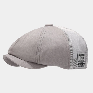 Detail of grey mesh beret showing side patch with vintage letters and breathable fabric