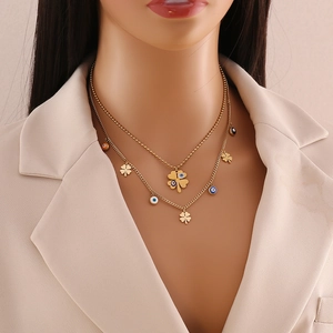 Close-up of gold double-layer necklace with blue evil eye and clover pendants on model