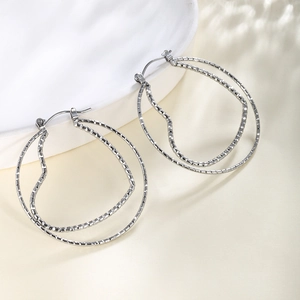 Macro detail of silver double-layer hoop earrings with textured wavy inner heart design