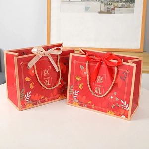 Red festive gift bag with gold handles and champagne ribbon for weddings and events