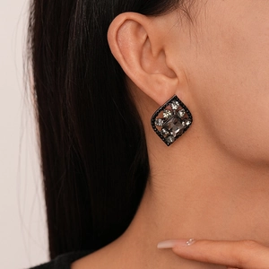 Dark style rhombus leaf stud earrings with gray crystals on a model's ear