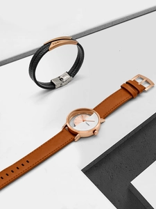 Close-up of TOMI rose gold watch with brown leather strap and black braided bracelet