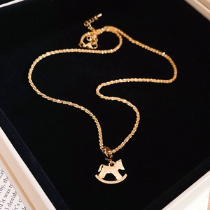 Detail of gold pony pendant with hammered texture resting in a black velvet jewelry box
