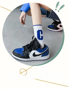 Close-up of white mid-calf athletic sock featuring blue letter C and elastic ribbed cuff