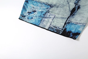 Detail of blue and teal abstract print fabric with fine black overlock stitching hem