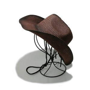 Close-up of dark brown straw sun hat with woven texture and black adjustable wind rope