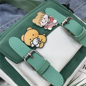 Detail of green and white nylon crossbody bag featuring cute cartoon character badges