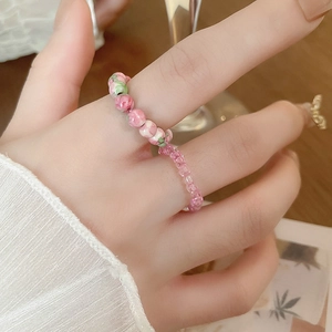Macro shot of two beaded elastic rings featuring pink flower patterns on the finger