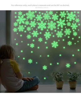 Close-up of luminous snowflake window stickers glowing in green on a glass surface