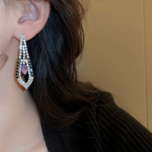 Detail of diamond-encrusted geometric tassel earrings with purple rhinestone centerpiece