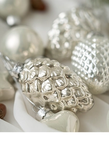 Detailed view of pearl white acorn and heart-shaped Christmas ornaments on white fabric