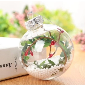 Clear PET Christmas ball filled with green leaves, red berries and foam snow on wood