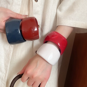 Detailed view of stacked irregular resin bangles in blue, red, marble, and white colors