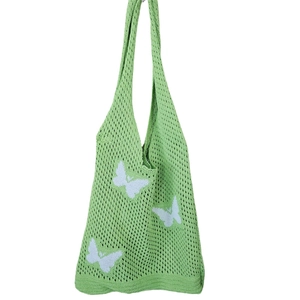 Dettaglio della borsa tote all'uncinetto verde con farfalla bianca e maglia a traforo