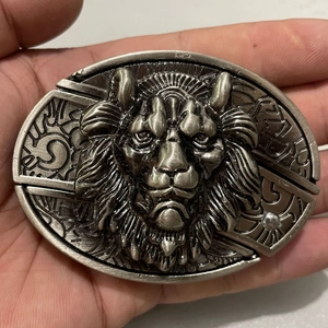 Detail of vintage silver lion head belt buckle with intricate 3D embossed metal carving
