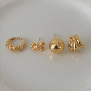 Flat lay of gold bow knot and twisted hoop earring set on cream ceramic surface
