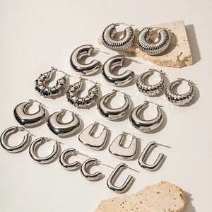Detailed set of silver stainless steel hoop earrings and U-shaped clips on stone surface