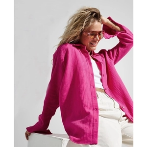 Relaxed fit rose red long sleeve cotton crepe shirt for women in a side sitting pose